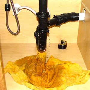 clogged sink trap overflowing water under sink causing water damage