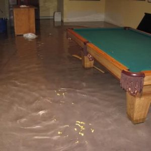 a flooded room in a basement, water is clearly visible on the floor at near ankle height