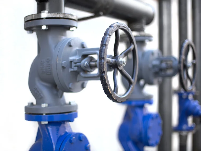 Close-up of blue industrial metal valves with handwheels attached to pipes, used in drain repair and plumbing in Toronto to control the flow of liquids or gases, against a blurred background.