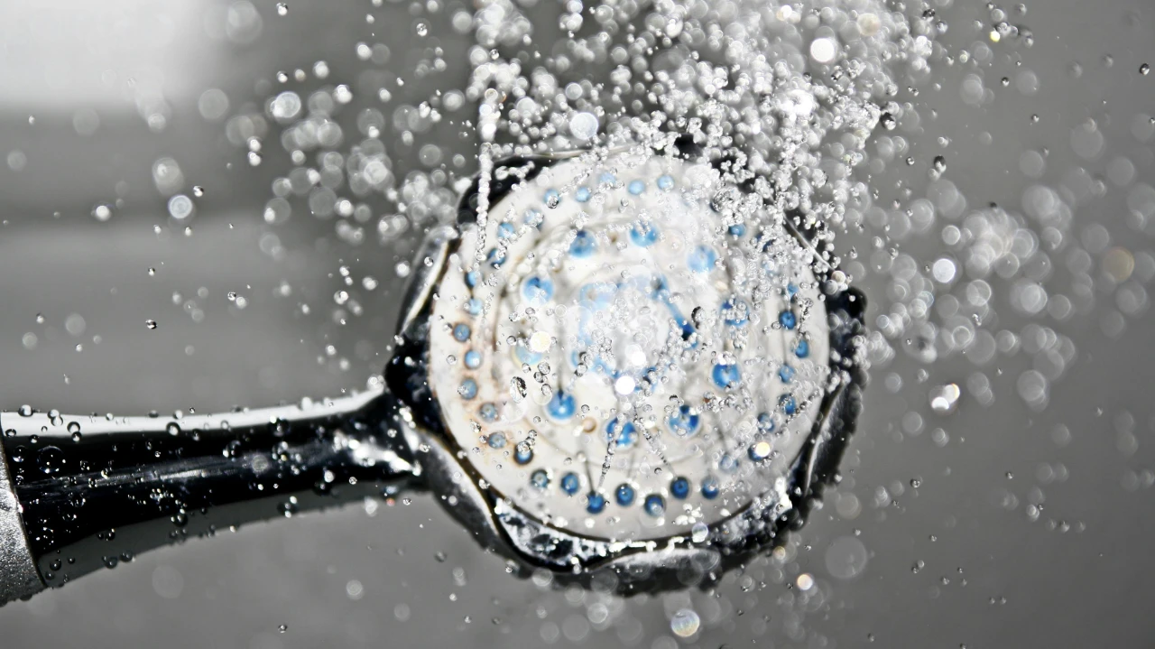 Close-up of a handheld showerhead spraying water, with droplets captured in motion and bokeh effect in the background, creating a dynamic and refreshing scene.